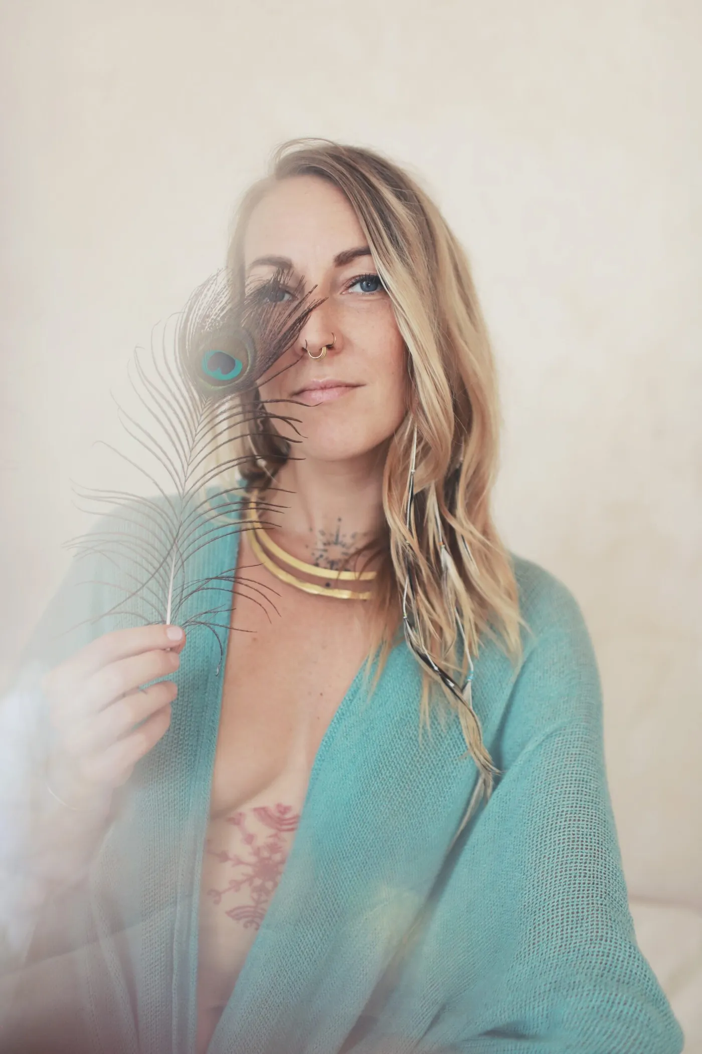 Linda Kaarina holding a peacock feather, looking into the camera