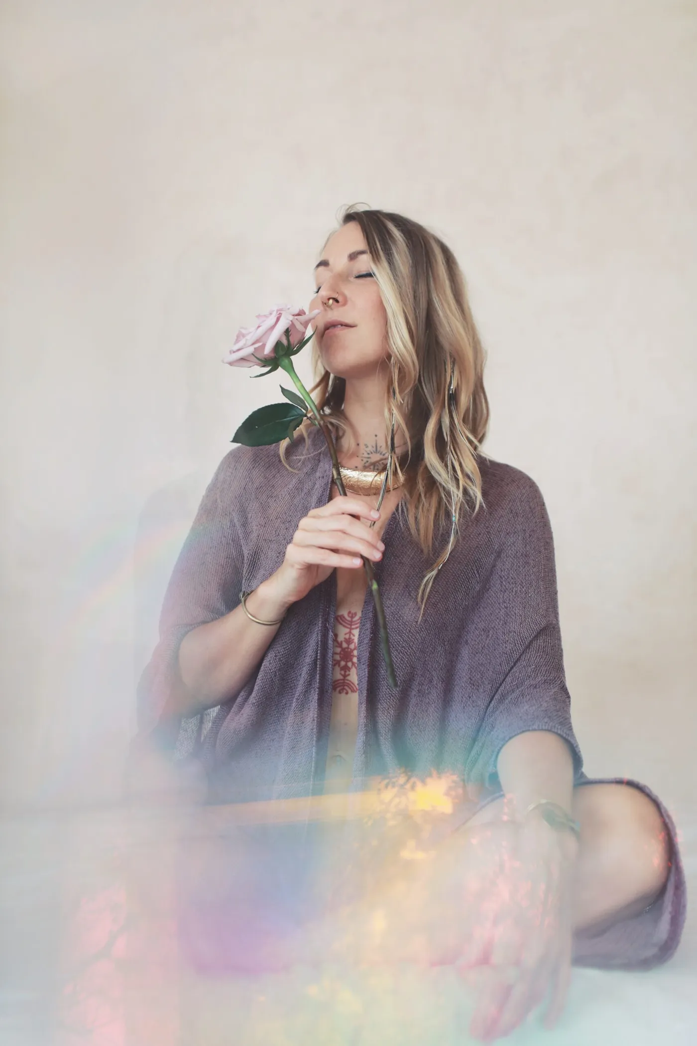 Linda Kaarina sitting, eyes closed, holding a rose to her face